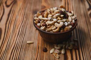 mixed nuts in a bowl on wooden table, top view with copy space. photo