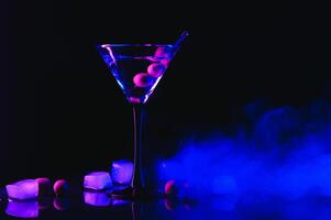 Martini glass and olives on a black background with neon lights photo