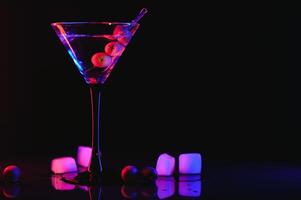 Martini cocktail drink splash with ice cubes in neon iridescent pink and blue colors. Minimal night party life concept. photo