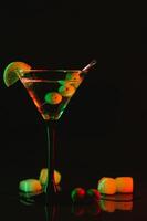 Martini glass and olives on a black background with neon lights photo