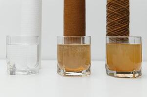 Water filters concept. Carbon cartridges and a three glasses on a white background. Household filtration system. photo