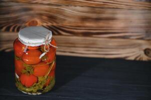 Jars of pickled vegetables on rustic wooden background photo