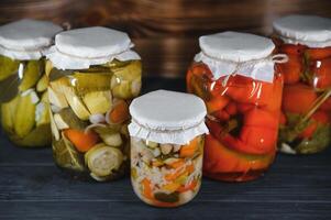 Jars of pickled vegetables on rustic wooden background photo