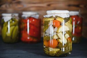 Canned cucumbers and tomatoes with craft lids on a wooden background. Cucumbers and tomatoes with place for text. Stocks of canned food. Harvest, stocks for the winter. photo