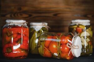 Jars of pickled vegetables on rustic wooden background photo