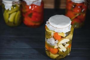 Jars of pickled vegetables on rustic wooden background photo