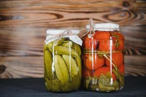 Jars of pickled vegetables on rustic wooden background photo