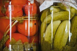 Enlatado pepinos y Tomates con arte tapas en un de madera antecedentes. pepinos y Tomates con sitio para texto. cepo de Enlatado alimento. cosecha, cepo para el invierno. foto