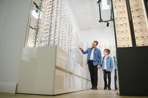 Dad and son choose new stylish glasses in an optical store. Vision care concept photo