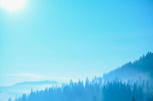 Mountain range with visible silhouettes through the morning blue fog. photo