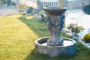 Fountain in the park garden. Water flows from the fountain. photo