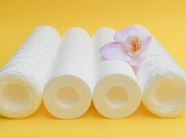 Water filters. Carbon cartridges and a glass on a yellow background. Household filtration system photo