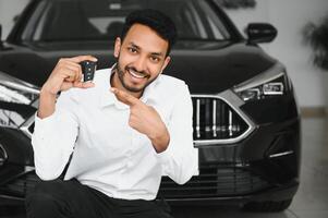 Successful indian businessman in a car dealership - sale of vehicles to customers. photo