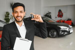 indian cheerful car salesman showing new car at showroom photo