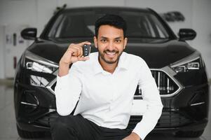 Successful indian businessman in a car dealership - sale of vehicles to customers. photo