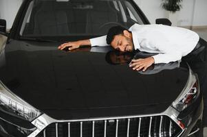 A young Indian man chooses a new car at a car dealership photo