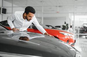 happy indian man buy new biodiesel eco automobile in lux showroom. photo