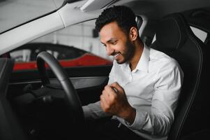 happy indian man checking car features at showroom photo