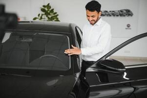 happy indian man checking car features at showroom photo
