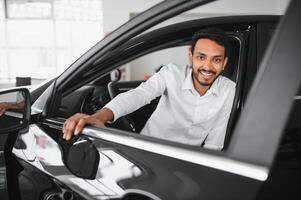 Young man sitting inside new car. Smiling photo