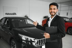 indian cheerful car salesman showing new car at showroom photo