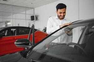 A young Indian man chooses a new car at a car dealership photo