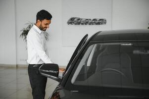 A young Indian man chooses a new car at a car dealership photo