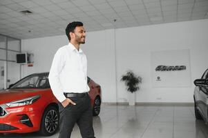 Successful indian businessman in a car dealership - sale of vehicles to customers. photo