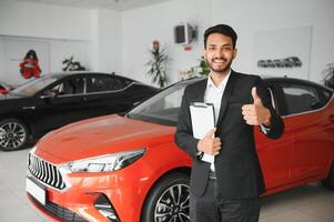 Successful indian businessman in a car dealership - sale of vehicles to customers. photo