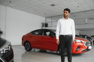 Successful indian businessman in a car dealership - sale of vehicles to customers. photo