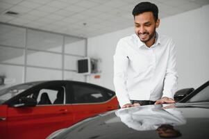 happy indian man buy new biodiesel eco automobile in lux showroom. photo