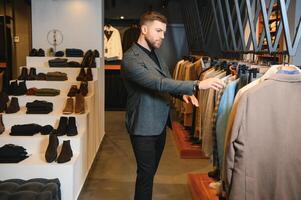 Businessman in classic vest against row of suits in shop photo