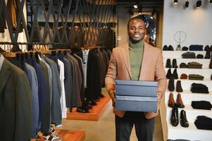 Joyful african american man carrying shopping bags in clothing store. Fashion boutique photo
