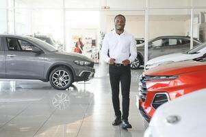 Portrait Of Handsome African American Salesman At Workplace In Car Showroom photo