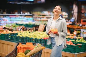 young adult woman choosing apples in grocery store. lifestyle photo