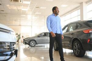 hermoso africano hombre elegir un nuevo coche a el concesión foto