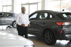 carros concesión concepto. auto vendedor afro hombre en pie en automóvil centrar foto