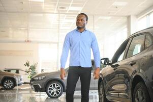 Handsome African man choosing a new car at the dealership photo