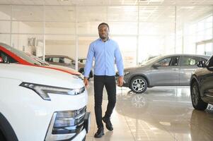 Handsome African man choosing a new car at the dealership photo