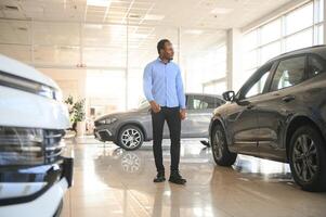 Car Buyer. Black Guy Choosing New Automobile In Dealership Store photo