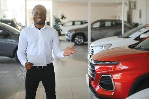 Portrait Of Handsome African American Salesman At Workplace In Car Showroom photo