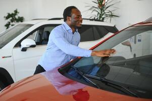 Handsome African man choosing a new car at the dealership photo