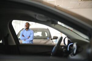 joven afroamericano hombre llegó a ver automóviles en concesión o carros sala de exposición foto