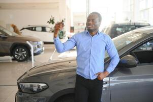 Happy smiling man holding car keys offering new car on background photo