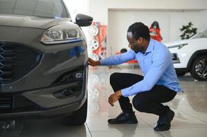 Handsome African man choosing a new car at the dealership photo