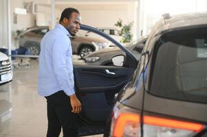 hermoso africano hombre elegir un nuevo coche a el concesión foto