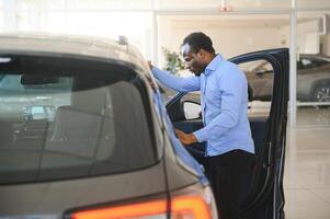 Car Buyer. Black Guy Choosing New Automobile In Dealership Store photo