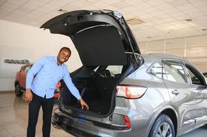 His dream car. Happy young African man looking excited choosing a car at the dealership photo