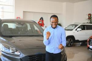 Car Buyer. Black Guy Choosing New Automobile In Dealership Store photo