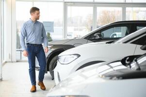 Concept of buying electric vehicle. Handsome business man stands near electric car at dealership photo